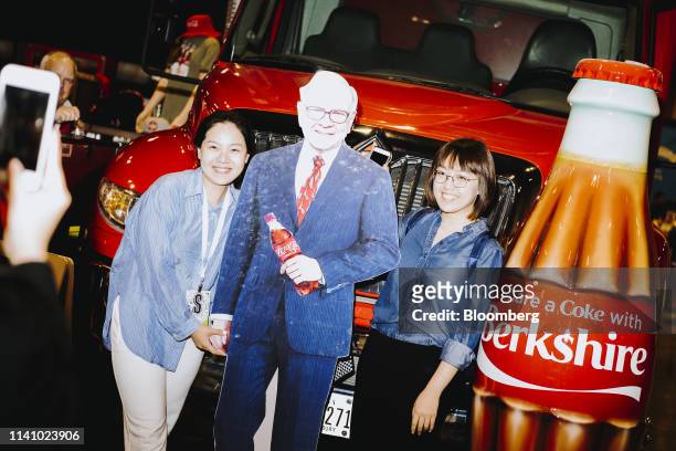 Attendees stand for a photograph with a cardboard cutout of Warren Buffett, chairman and chief executive officer of Berkshire Hathaway Inc., during a...