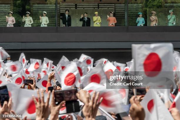 People wave Japanese flags as Emperor Naruhito of Japan waves to members of the public as his wife, Empress Masako , and other members of the...