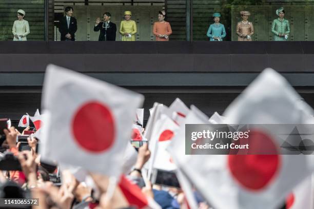 People wave Japanese flags as Emperor Naruhito, accompanied by his wife, Empress Masako, and other members of the Japanese royal family, waves from...