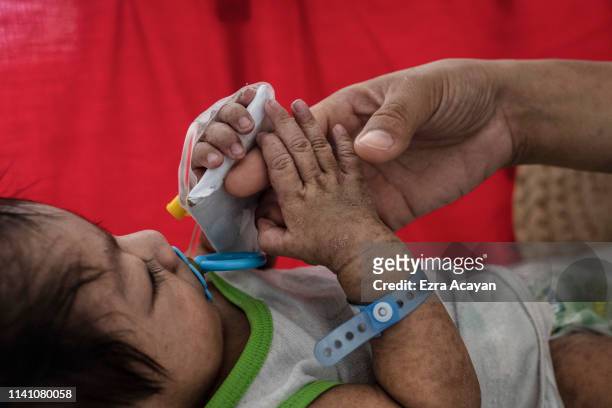 Iris Ladrillo tends to her four-month-old son Mark Robin, who is suffering from measles and being treated at a government-run hospital on May 4, 2019...