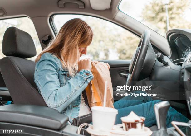 young woman opening take out food bag in a car - chunky chips stock pictures, royalty-free photos & images