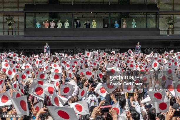 People wave Japanese flags as Emperor Naruhito of Japan waves to members of the public as his wife, Empress Masako, and other members of the Japanese...