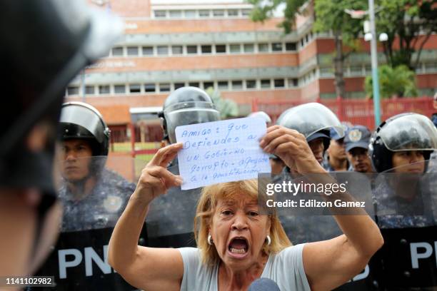 Woman speaks as she shows a sign in front of members of the Venezuelan National Police during a protest at the Comandancia General de la Armada of...