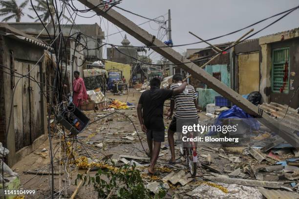 People walk underneath damaged electric cabling in Cyclone Fani passes in the Puri district of Odisha, India, on Saturday, May 4, 2019. A category 4...