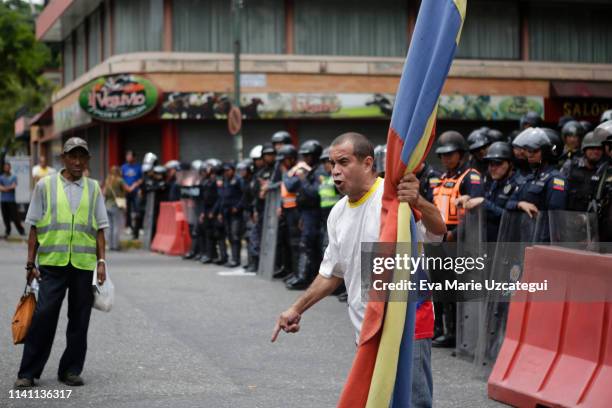 Man holds a flag in front of Venezuelan National Police during a demonstration answering to Guaidó's call for peaceful demonstrations to continue...