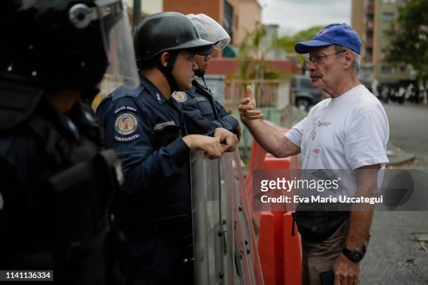 Man speaks to riot police officers during a demonstration answering to Guaidó's call for peaceful demonstrations to continue near La Casona on May 4,...