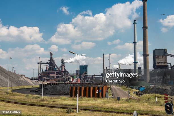 steel mill with smoking chimneys and heaps of raw material - condensation furnace stock pictures, royalty-free photos & images