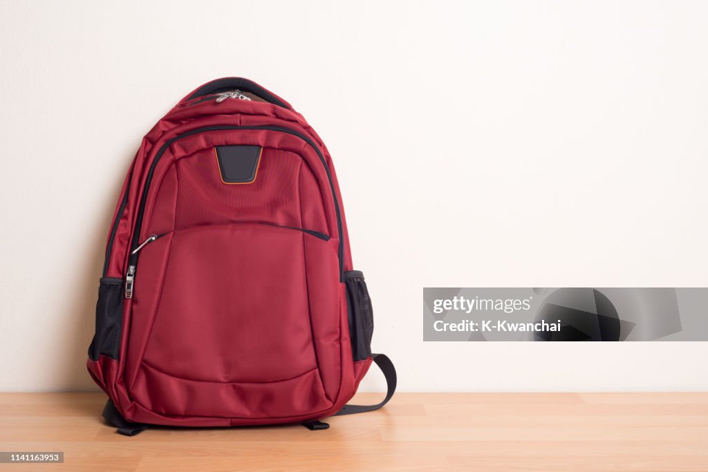 Red Backpack On Hardwood Floor Against Wall