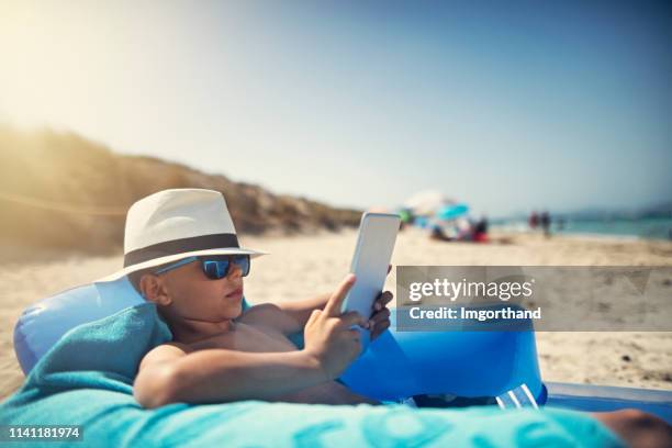 un niño tomando el sol en la playa - modo de vida no saludable fotografías e imágenes de stock