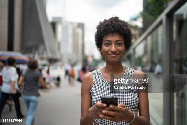 jonge zakenvrouw met mobiel portret op de stad - brazilian woman stockfoto's en -beelden