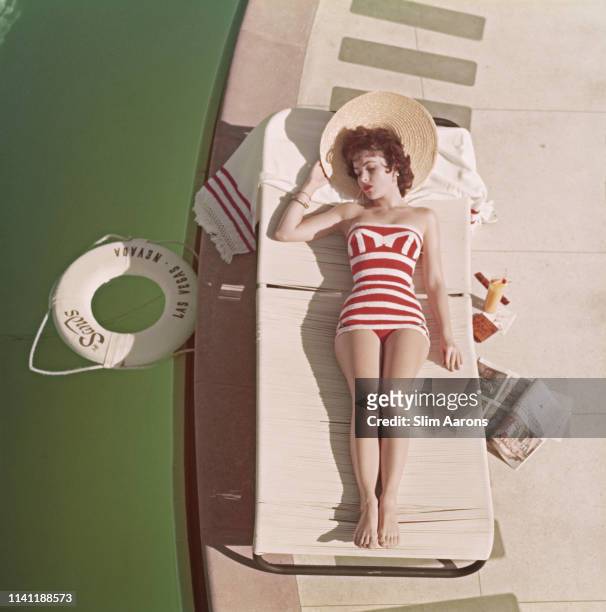 Austrian actress Mara Lane lounging by the pool in a red and white striped bathing costume at the Sands Hotel, Las Vegas, 1954.