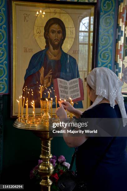 Woman lighting candles at a Russian Orthodox church service in Volgograd on the Volga river, Russia.