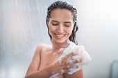 Smiling female rubbing body with foam