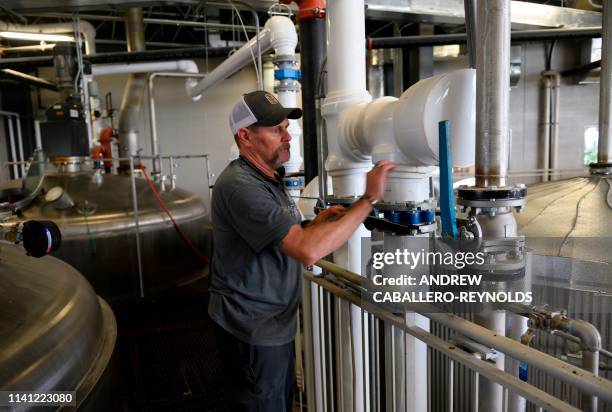 An employee at the Bardstown Bourbon Company opens pipes to one of the corn mash mixers in Bardstown, Kentucky on April 11, 2019. - To be called...