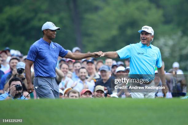 Tiger Woods of the United States celebrates with Fred Couples of the United States on the 12th tee during a practice round prior to The Masters at...