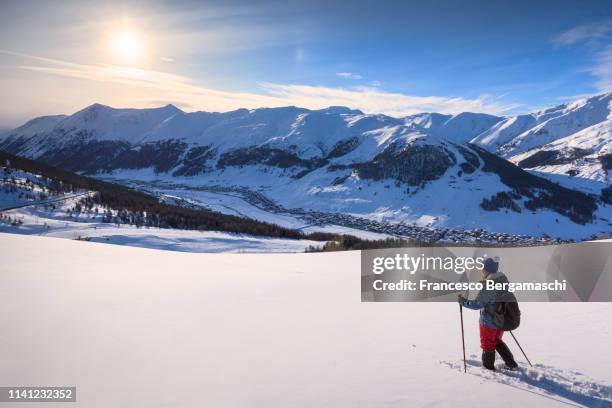 girl with snowshoes looks the landscape. livigno, valtellina, lombardy, italy, europe. - livigno - fotografias e filmes do acervo