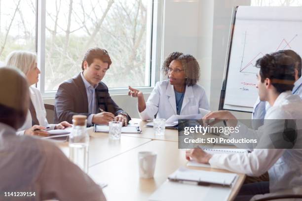 mature doctor discusses something during conference - healthcare and medicine business stock pictures, royalty-free photos & images