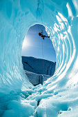 Man hanging from a rope inside large ice cave of the Matanuska Glacier in Alaska's backcountry.