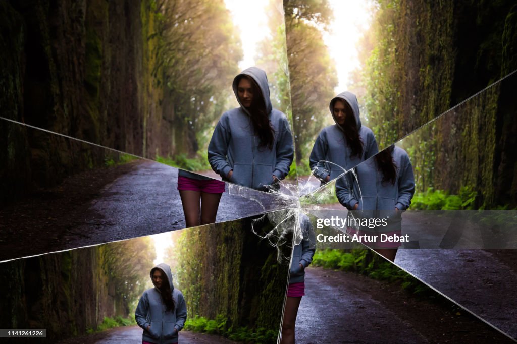 Mystic picture of woman walking in the deep forest seen through a broken mirror.