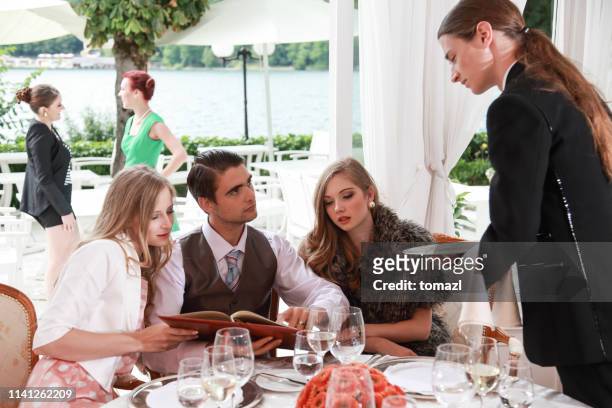 jeune homme riche ayant le diner avec ses copines - mafia food photos et images de collection
