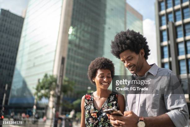 business partners laughing and using mobile on the city - man on cell phone walking in the city stock pictures, royalty-free photos & images