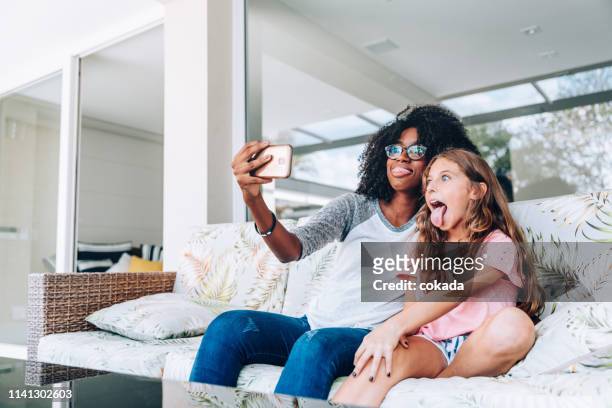 dos jóvenes amigos haciendo caras graciosas mientras toman un selfie - au pair fotografías e imágenes de stock