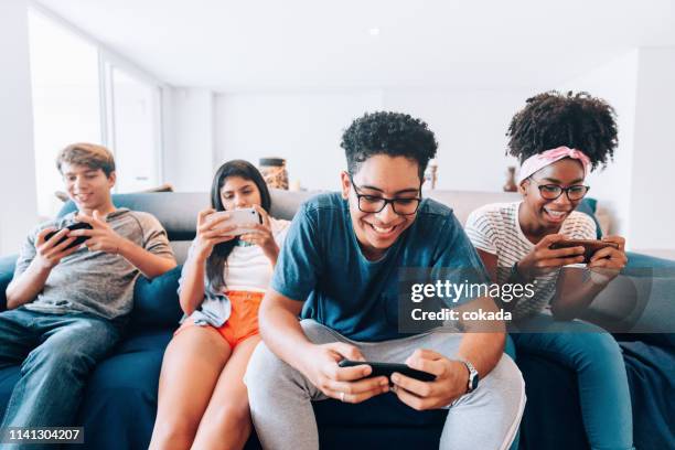 group of young friends playing mobile games on smartphone - mobile game stock pictures, royalty-free photos & images