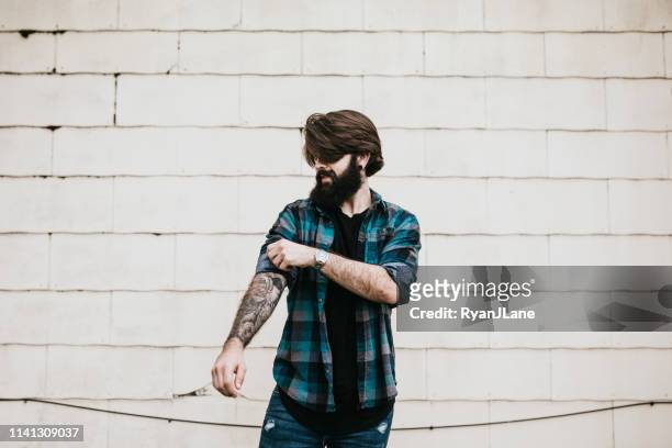 porträt handgreiflicher mann durch mauer - rolling up sleeve stock-fotos und bilder