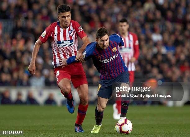 Lionel Messi of FC Barcelona competes for the ball with Rodrigo Hernandez of Club Atletico de Madrid during the La Liga match between FC Barcelona...