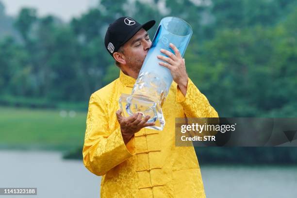 Finland's Mikko Korhonen kisses the trophy after winning the China Open golf tournament in Shenzhen, in China's southern Guangdong province on May 5,...