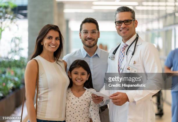 porträt des schönen paares und ihre tochter stehen neben dem kinderarzt im krankenhaus alle lächelnd - handsome doctors stock-fotos und bilder