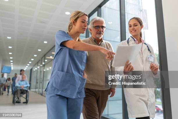 freundlicher arzt und krankenschwester im gespräch mit einem älteren patienten im krankenhaus, während einige dokumente - the resident screening stock-fotos und bilder