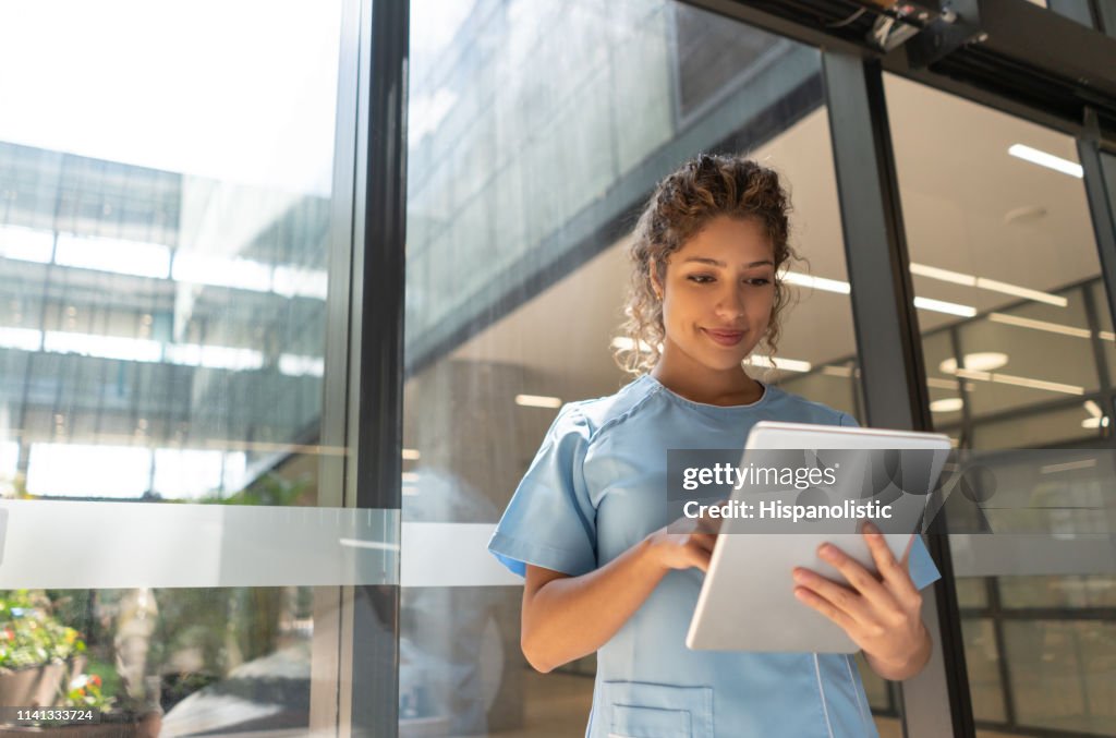 Friendly young nurse looking at a medical chart on tablet slightly smiling
