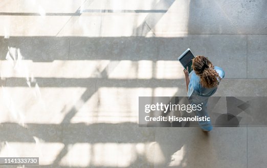 High angle view of nurse walking around hospital while looking at a medical chart on tablet High angle view of nurse walking around hospital while looking at a medical chart on tablet