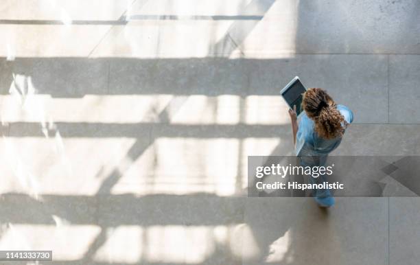 high angle view of nurse walking around hospital while looking at a medical chart on tablet - electronic medical record concept stock pictures, royalty-free photos & images