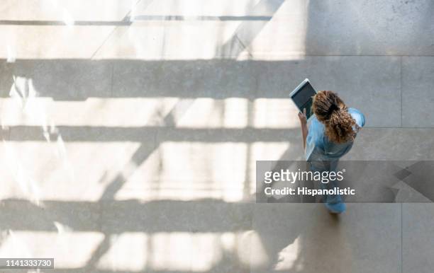 high angle view of nurse walking around hospital while looking at a medical chart on tablet - overhead view imagens e fotografias de stock