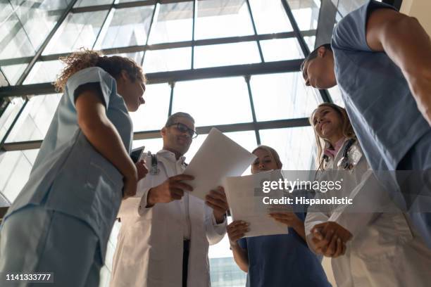team of doctors and nurses in a meeting looking at some documents - civilian stock pictures, royalty-free photos & images