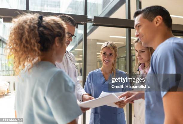 team of healthcare professionals talking while looking at documents in the hospital - resident stock pictures, royalty-free photos & images