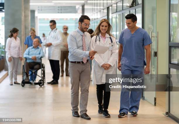 el gerente del hospital mostrando un documento al médico y al enfermero sonriendo - hospital staff fotografías e imágenes de stock