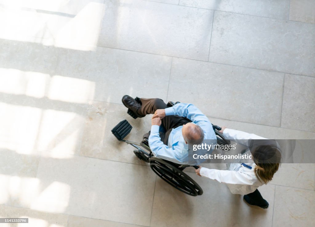 Female doctor pushing male patient on wheelchair at the hospital