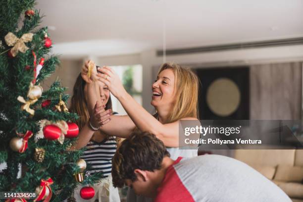 family decoranting the christmas tree at home - family decorating stock pictures, royalty-free photos & images