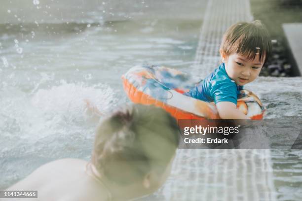 love and care:thai son with inflatable ring while looking his father for teaching to swimming with care emotion at the swimming pool - ring swimming pool stock pictures, royalty-free photos & images