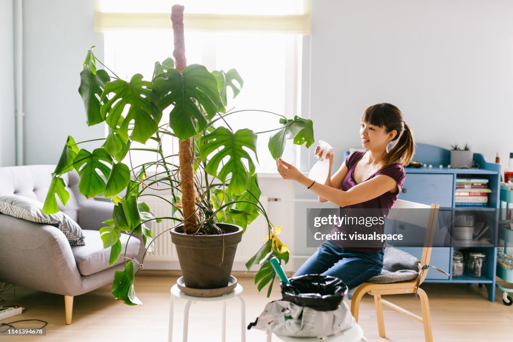 笑顔アジアの女性植物に水を噴霧