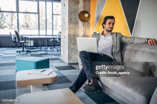 zakenman zittend op sofa in modern office - cool office stockfoto's en -beelden