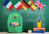 backpack, flags of Spain, France, Great Britain and other countries, books and school supplies of the blackboard