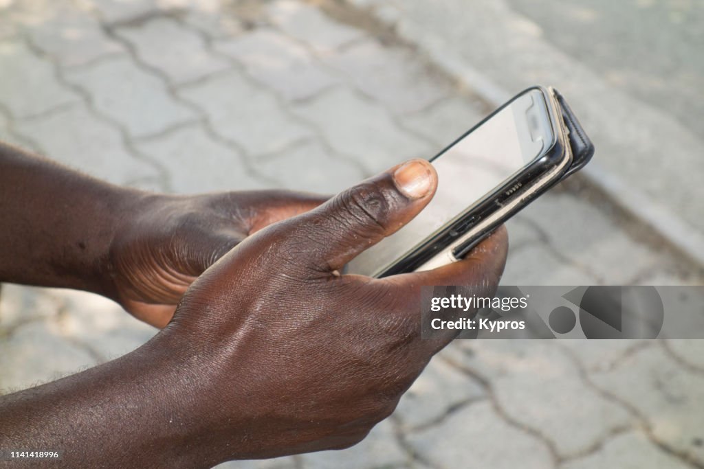 View Of Refugee (Migrant Worker) From Dakar, Senegal Using Smartphone (Close Up Of Hands)