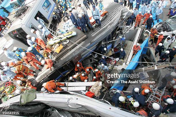 Rrescue workers attempt to free trapped passengers from a crushed commuter train after it derailed and plunged into an apartment building on April...