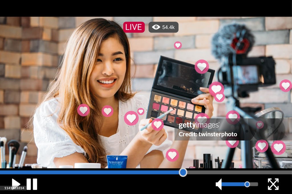Frau macht Make-up während der Aufnahme von Live-Stream mit Video-Player-Schnittstelle