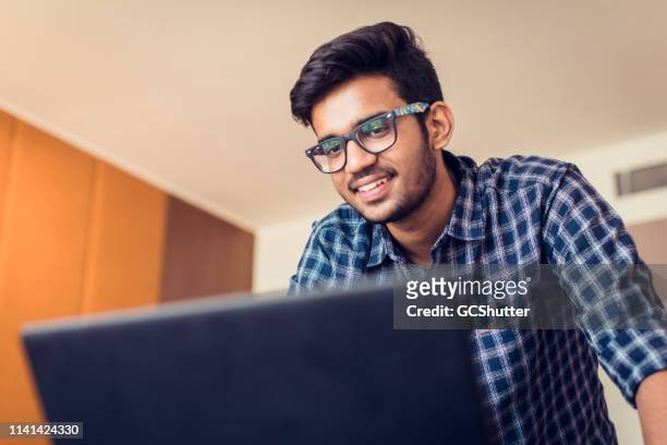 jonge man het doen van een video-conferencing met zijn laptop - indian subcontinent ethnicity stockfoto's en -beelden