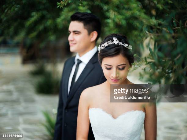 lovely bride looking down and groom in background - front on groom and bride stock pictures, royalty-free photos & images